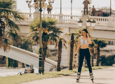 Young girl roller skating down on a road on summer day