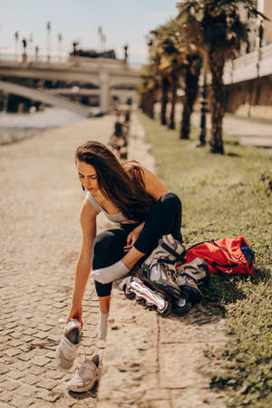 Gorgeous girl is prepairing for skating near the river