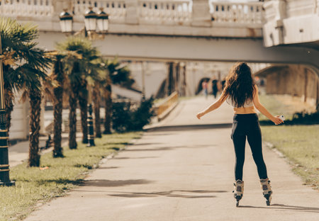 Urban girl is in the park, looking happy while roller skating