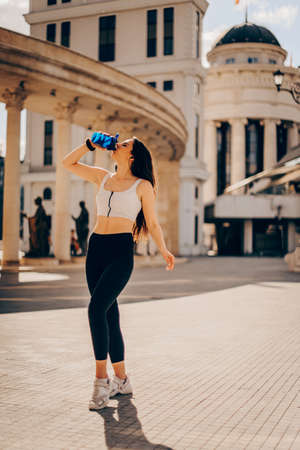 Sporty girl drinking water from a shaker after a workout, fitness trainingの写真素材