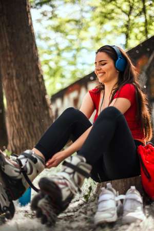 Girl going rollerblading sitting putting on inline skatesの写真素材