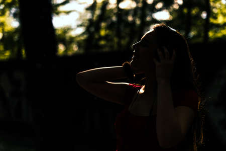 Portrait of a cheerful cute woman listening music in headphones in the park