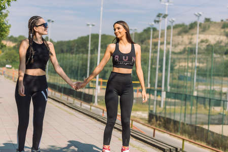 Two beautiful sportswomen roller skating in the park on a sunny dayの写真素材