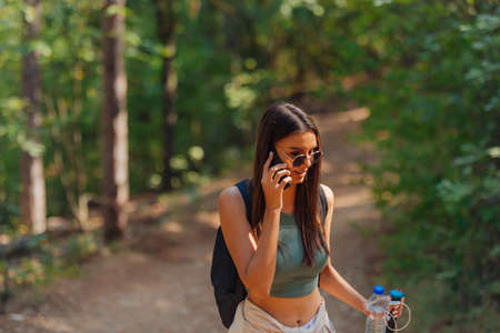 Sisters hiking through beautiful woods while wearing a backpack and enjoying nature. Female bonding.の写真素材