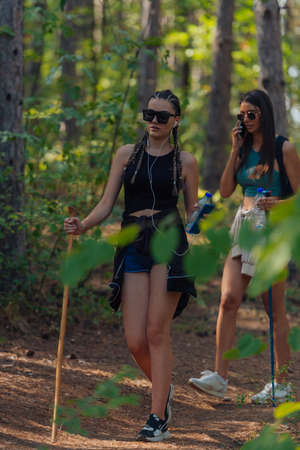 Sisters hiking through beautiful woods while wearing a backpack and enjoying nature. Female bonding.の写真素材