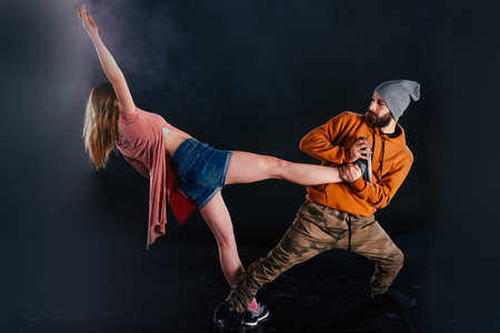 Couple dancing modern dance and showing off their leg stretch moves.Black background while the...