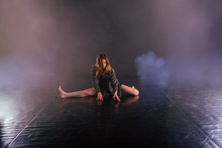 Shoeless female dance shows off her modern art dance moves while looking serious and devoted.