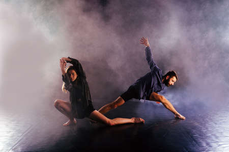 Modern dance couple twisting their legs and lening close to the ground, touching and combining their bodies in extremely unique modern dance experience.の写真素材