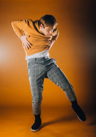 Caucasian male dancer exercising a contemporary dancing on orange wallの写真素材