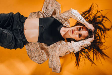 Flexible athletic girl during an intense dance exercise in modern orange studioの写真素材