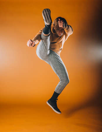 Caucasian male dancer exercising a contemporary dancing on orange wallの写真素材