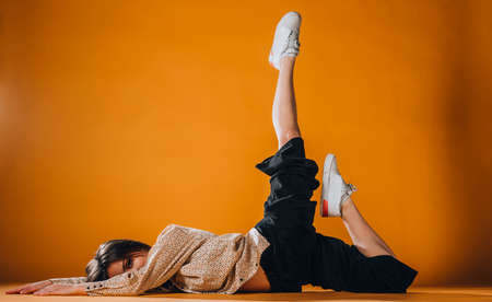 Caucasian female dancer exercising a contemporary dancing on orange wallの写真素材