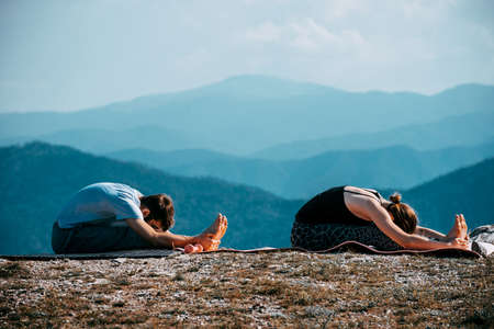 Young couple practicing yoga in the nature. Couple happiness. Landscape background