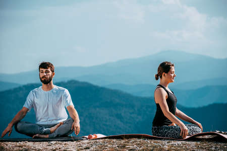 Man and woman doing pair yoga outdoor in a mountain Fit young couple practising acroyoga.の写真素材