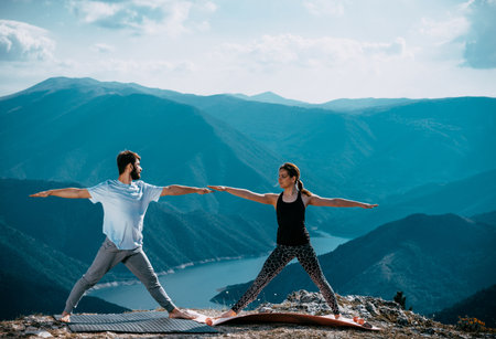 Young couple practicing yoga in the nature. Couple happiness. Landscape backgroundの写真素材