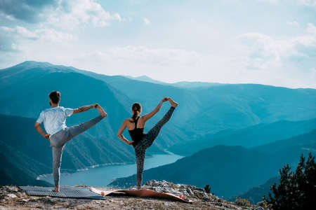 Yoga at summit with aerial view of the mountain range and peak. Blue skyの写真素材