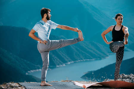 Young yoga couple training at sunrise mountain peakの写真素材