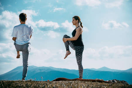 Yoga retreat, fitness, sport and lifestyle concept - smiling couple making yoga exercisesの写真素材