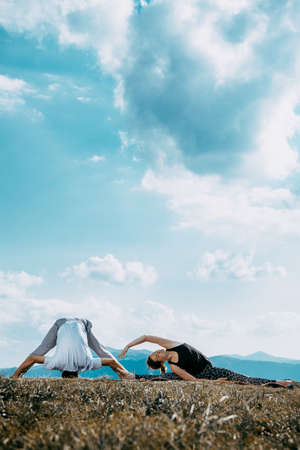 Man and woman doing pair yoga outdoor in a mountain Fit young couple practising acroyoga.の写真素材