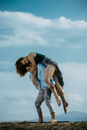 Summer holidays, love, relationship and dating concept - smiling couple dancing on the mountain peakの写真素材