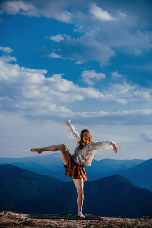 Passionate young woman dancer in a beautiful dreamy pose with one leg up in the airの写真素材