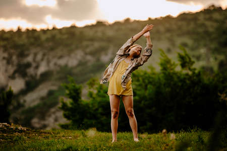 Modern style silhouette female dancer while dancing in skirt against sunset skyの写真素材