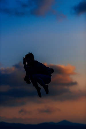 Handsome young dancer performing modern dance over blue skyの写真素材