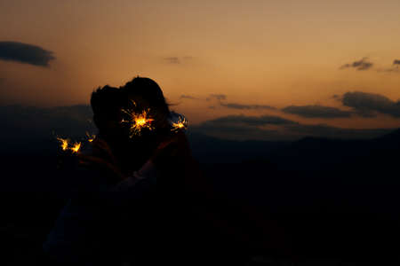 Shot of a young people playing with sparklers at night. Best friends hanging out at nightの写真素材