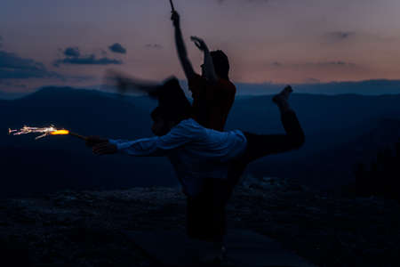 Young beautiful barefoot couple dancer practicing modern dance while holding firesticksの写真素材