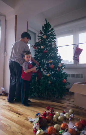Two happy boys decorating the Christmas tree,while smiling and having fun.の写真素材