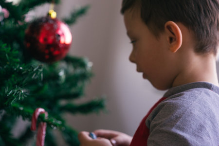 Cute kid is decorating his family Christmas tree while spreading the Christmas spirit in his family.の写真素材