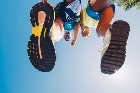 Bottom view cropped image of two people in sneakers while running