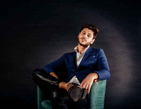 A potrait of a charming young man sitting in vintage sofaの写真素材