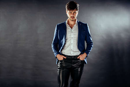 Portrait of a handsome young man wearing leather jeans and suitの写真素材