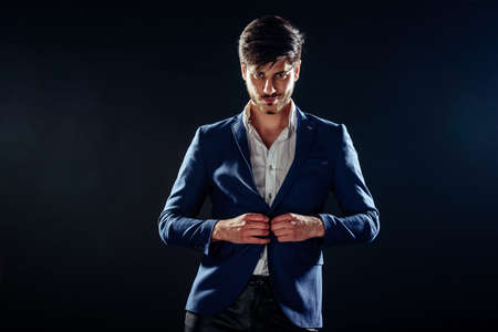 Portrait of a handsome young businessman leaning against black wall backgroundの写真素材