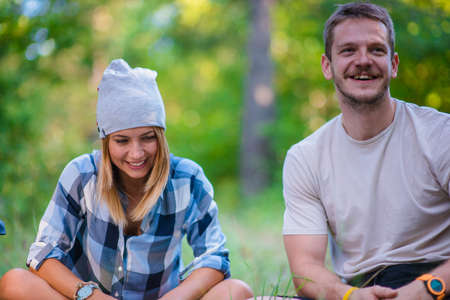 Young couple resting and checking the map inside the forest. Hiking concept in the mountain in...