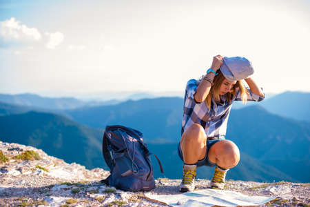 A woman putting on her hat on the peak of the mountain, cliff at sunset. Success, winner.