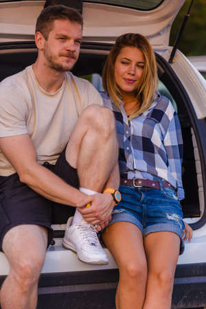 Young couple sitting on the back of a off road vehicle and enjoying the view from inside the all terrain vehicle at sunset.の写真素材
