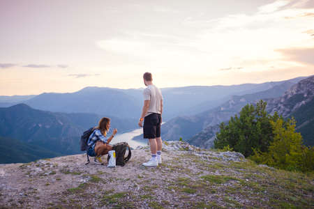 Eating chips on the mountain top. A couple enjoying the view on a peak of the mountain having a zen moment at sunset.の写真素材
