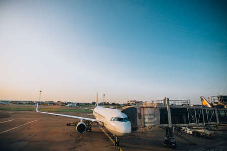 Big airplane with a jet bridge ready to be boarded by passangers at the airportの写真素材