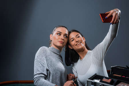 Stylish cheerful girls posing to take a selfie with a smartphoneの写真素材
