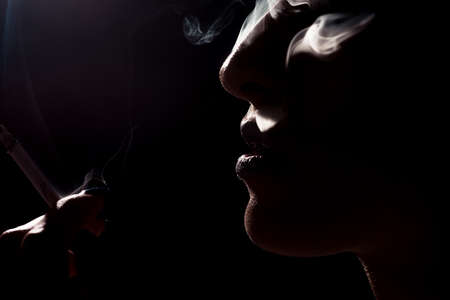 Smoking, Brunette woman with smoke coming out of her lips, concept smoker and tobacco