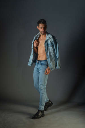 Handsome muscular shirtless young man standing confident, profile view, looking at cameraの写真素材