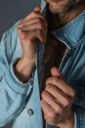 Picture of a young handsome macho man with abs and open denim jacket and jeans.