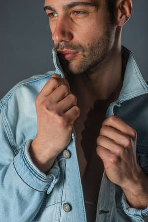 Picture of a young handsome macho man with abs and open denim jacket and jeans.の写真素材
