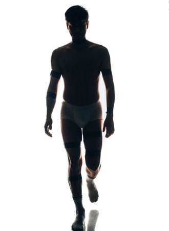 Sexy shirtless silhouette man in white underpants posing over white wallの写真素材