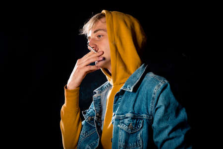 Attractive young male model posing with cigarette and yellow hoodieの写真素材
