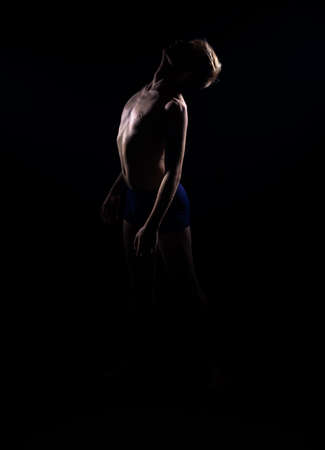 Studio fashion portrait of a handsome shirtless guy isolated on black backgorundの写真素材