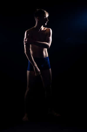 Artistic dance moves performed by an athletic caucasian guy against black wallの写真素材