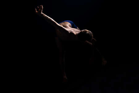 Modern semi nude dancer performing an artistic contemporary dance over black backgroundの写真素材